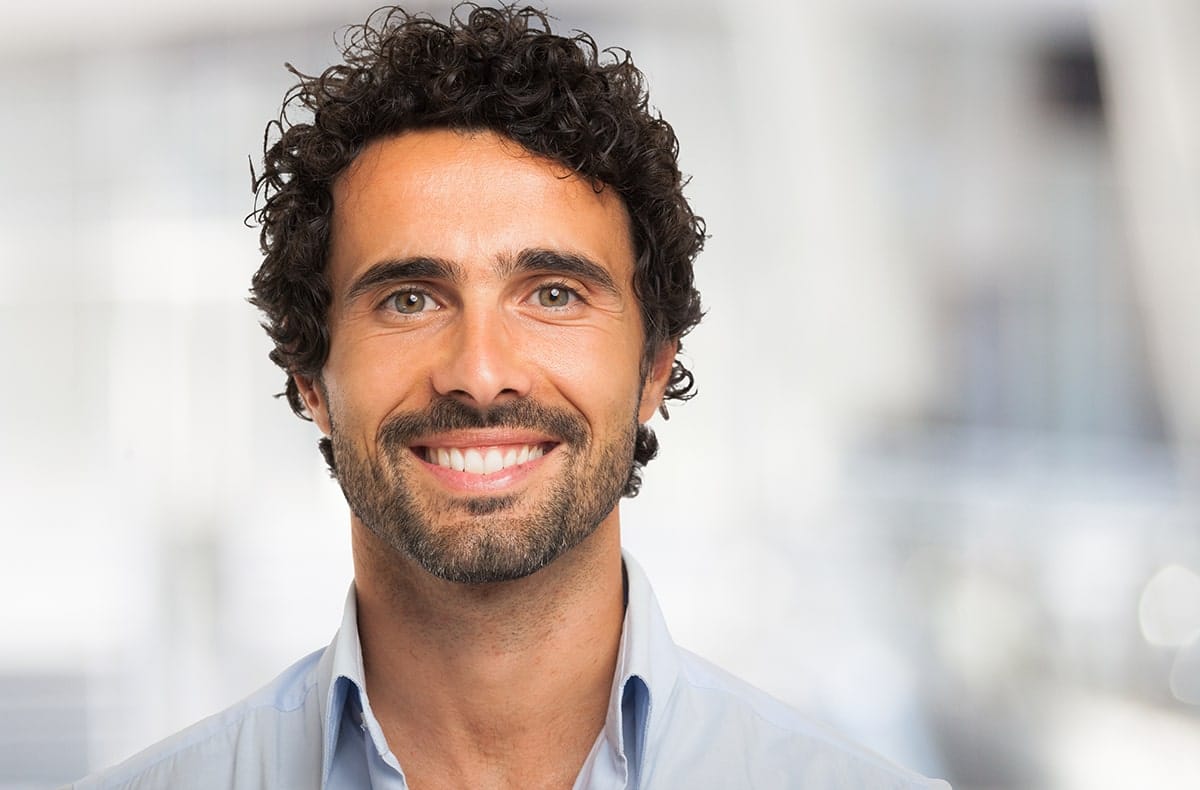 Should you travel for your dentist man with short, curly hair shows off his amazing smile